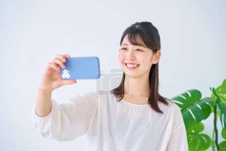 Téléchargez les photos : Jeune femme regardant l'écran du smartphone à l'intérieur - en image libre de droit