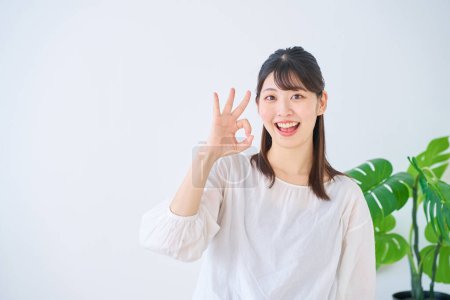 Téléchargez les photos : Jeune femme donnant un signe OK main à l'intérieur - en image libre de droit