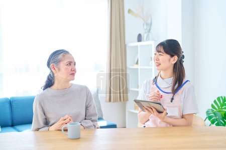 Photo for Young woman in apron and senior woman having a conversation at home - Royalty Free Image