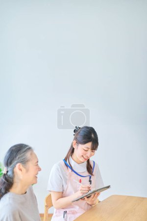 Young woman in apron and senior woman having a conversation at home