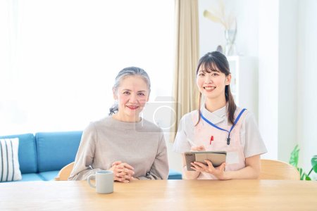 Téléchargez les photos : Jeune femme en tablier et femme âgée ayant une conversation à la maison - en image libre de droit