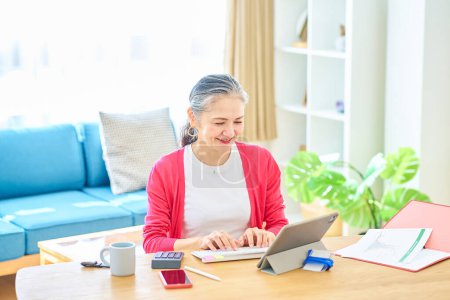 Photo for A senior woman operating a computer in a bright room - Royalty Free Image