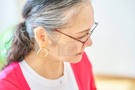 Téléchargez les photos : Une femme âgée portant des lunettes dans la chambre - en image libre de droit