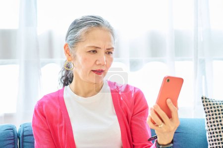 Foto de Una mujer mayor mirando la pantalla de su teléfono inteligente con una expresión problemática en el interior - Imagen libre de derechos