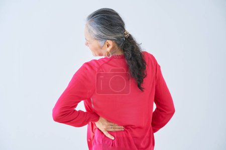 Téléchargez les photos : Vue arrière d'une femme âgée souffrant de maux de dos à l'intérieur - en image libre de droit