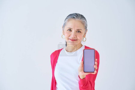 Téléchargez les photos : Femme âgée montrant l'écran de smartphone à l'intérieur - en image libre de droit