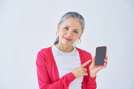 Téléchargez les photos : Femme âgée pointant vers smartphone à l'intérieur - en image libre de droit