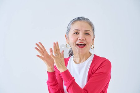 Téléchargez les photos : Femme âgée applaudissant avec un sourire à l'intérieur - en image libre de droit