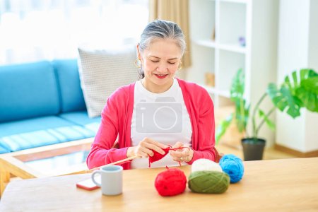 Photo for Senior woman enjoying knitting yarn in the room - Royalty Free Image
