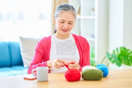 Téléchargez les photos : Femme âgée appréciant le fil à tricoter dans la chambre - en image libre de droit