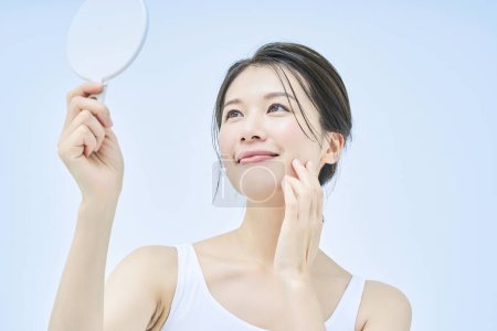 Téléchargez les photos : Une femme vérifie son état de peau avec un miroir de main - en image libre de droit
