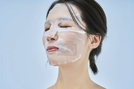 Foto de Una mujer que cuida su piel usando una compresa facial - Imagen libre de derechos