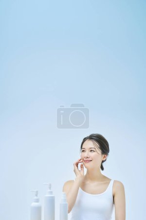 Téléchargez les photos : Femme faisant des soins de la peau et fond bleu pâle - en image libre de droit