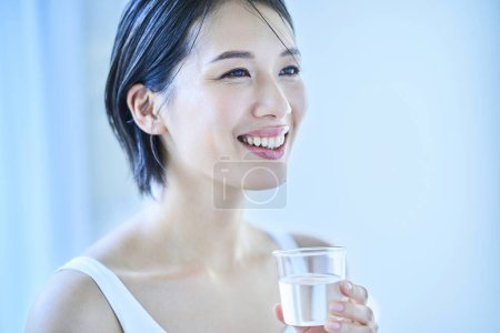 Foto de Mujer bebiendo un vaso de agua en la habitación - Imagen libre de derechos