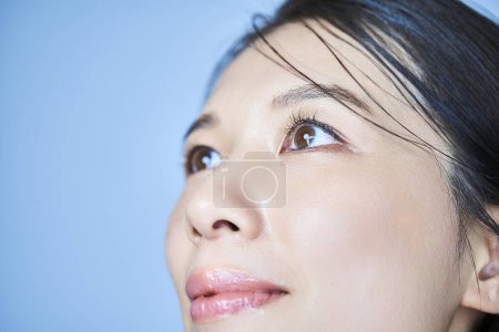 Téléchargez les photos : Gros plan des yeux d'une femme et fond bleu pâle - en image libre de droit