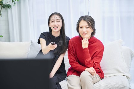 Téléchargez les photos : Deux femmes regardant la télévision dans la chambre - en image libre de droit