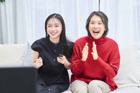 Téléchargez les photos : Deux femmes s'excitent en regardant la télé - en image libre de droit