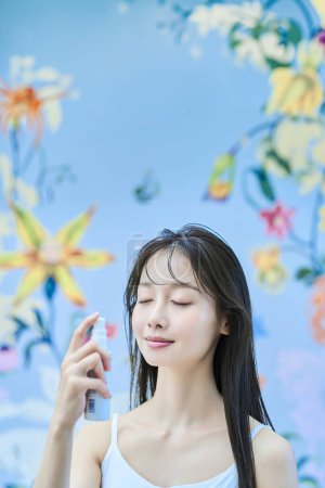 Photo for Young woman spraying her face in the room - Royalty Free Image