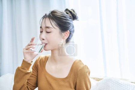 Photo for Young woman drinking water by the window - Royalty Free Image