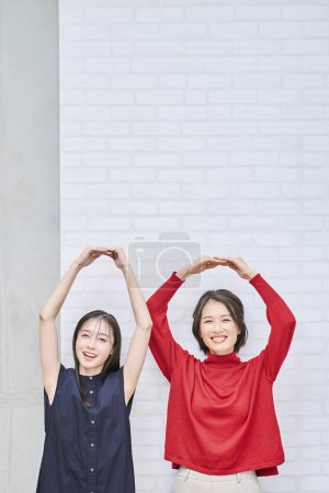 Foto de Dos mujeres sonriendo y dando una señal de mano OK - Imagen libre de derechos