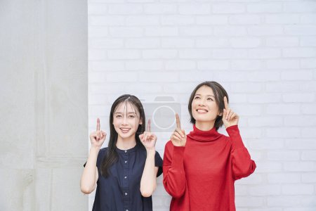 Photo for Two Japanese women pointing upwards indoors - Royalty Free Image