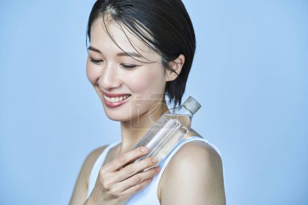 Téléchargez les photos : Une femme tenant une bouteille remplie de liquide transparent - en image libre de droit