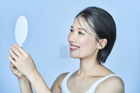 Photo for A woman looking at her face in a hand mirror - Royalty Free Image