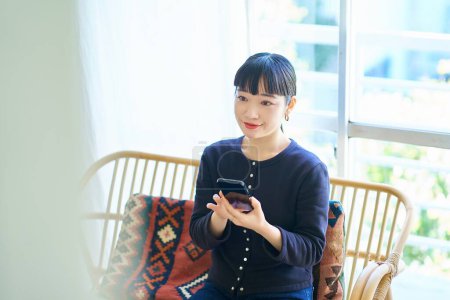 Photo for Young woman operating a smartphone in the room - Royalty Free Image