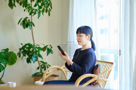 Photo for Young woman operating a smartphone in the room - Royalty Free Image