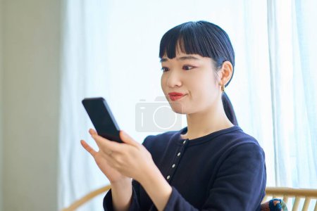 Foto de Mujer joven operando un teléfono inteligente en la habitación - Imagen libre de derechos