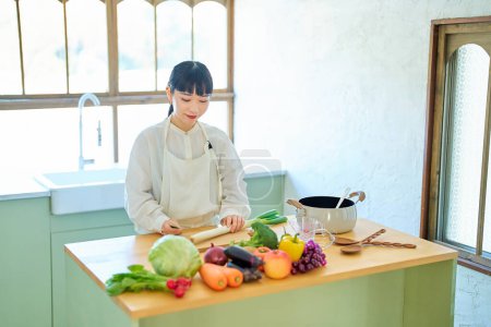 Téléchargez les photos : Jeune femme coupe les ingrédients avec un couteau à la cuisine - en image libre de droit