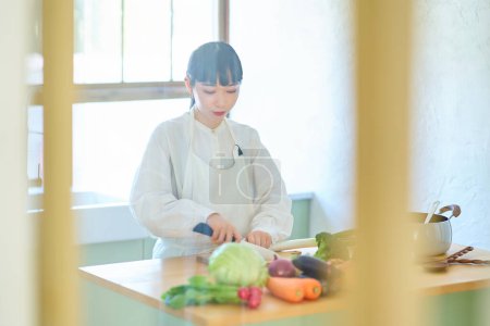 Photo for Young woman cutting ingredients with a knife at kitchen - Royalty Free Image