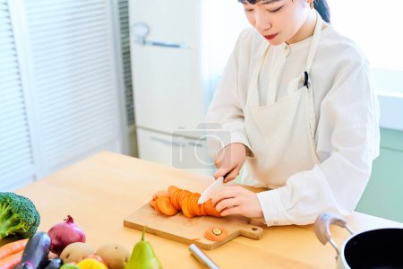 Téléchargez les photos : Jeune femme coupe les ingrédients avec un couteau à la cuisine - en image libre de droit
