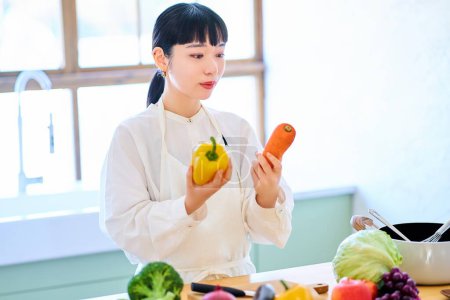 Foto de Mujer joven recogiendo verduras en la cocina - Imagen libre de derechos