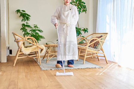 Téléchargez les photos : Jeune femme nettoyer le plancher dans la chambre - en image libre de droit