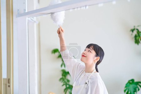 Photo for Young woman cleaning dust from every corner of the room - Royalty Free Image