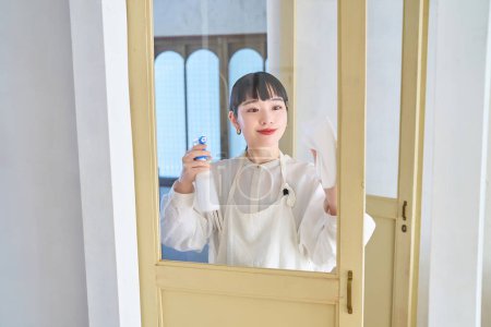 Photo for Young woman cleaning the glass in the room - Royalty Free Image