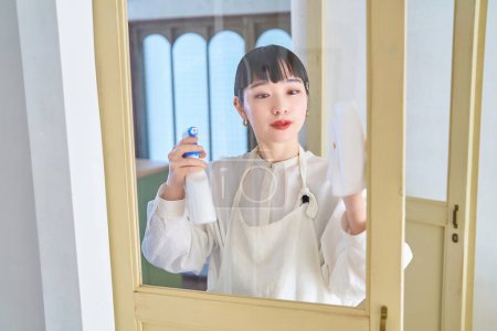 Foto de Mujer joven limpiando el vidrio en la habitación - Imagen libre de derechos