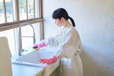 Téléchargez les photos : Jeune femme qui nettoie l'évier dans la chambre - en image libre de droit