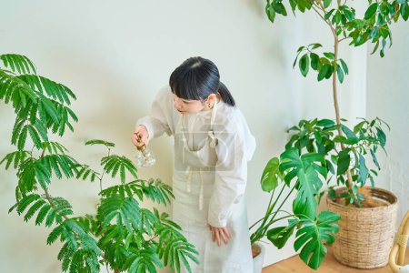 Photo for A young woman watering the houseplants in the room - Royalty Free Image