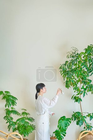 Una joven regando las plantas de interior en la habitación