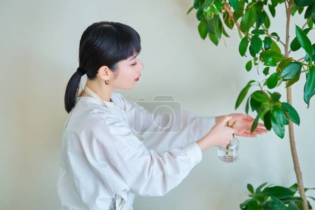 Une jeune femme arrosant les plantes d'intérieur dans la chambre