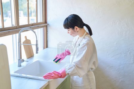 Photo for Young woman cleaning the kitchen sink in the room - Royalty Free Image