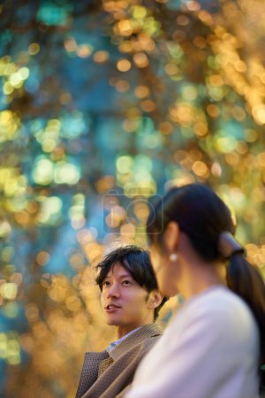 Photo for A man happily talking to a woman in an illuminated cityscape - Royalty Free Image