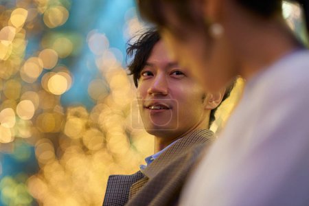 Photo for A man happily talking to a woman in an illuminated cityscape - Royalty Free Image