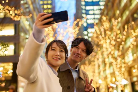 Téléchargez les photos : Un homme et une femme aiment prendre des photos lors d'une vue nocturne des illuminations - en image libre de droit