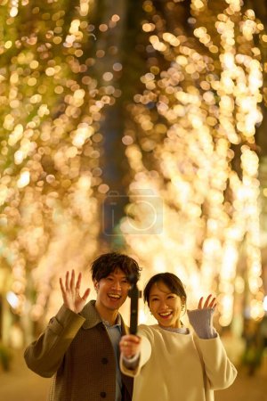 Photo for A man and a woman enjoy taking photos at a night view of illuminations - Royalty Free Image