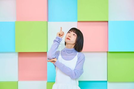 Photo for Young woman pointing upwards and colorful background - Royalty Free Image