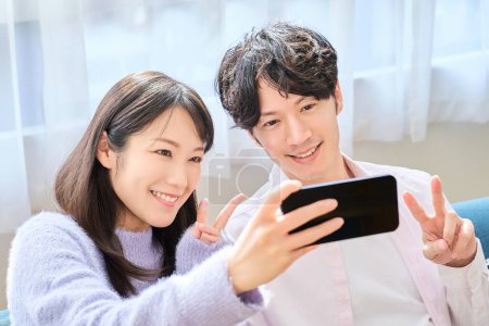 Young man and woman looking at smartphone screen in the room