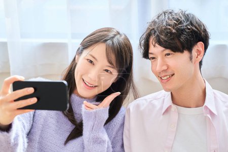 Young man and woman looking at smartphone screen in the room